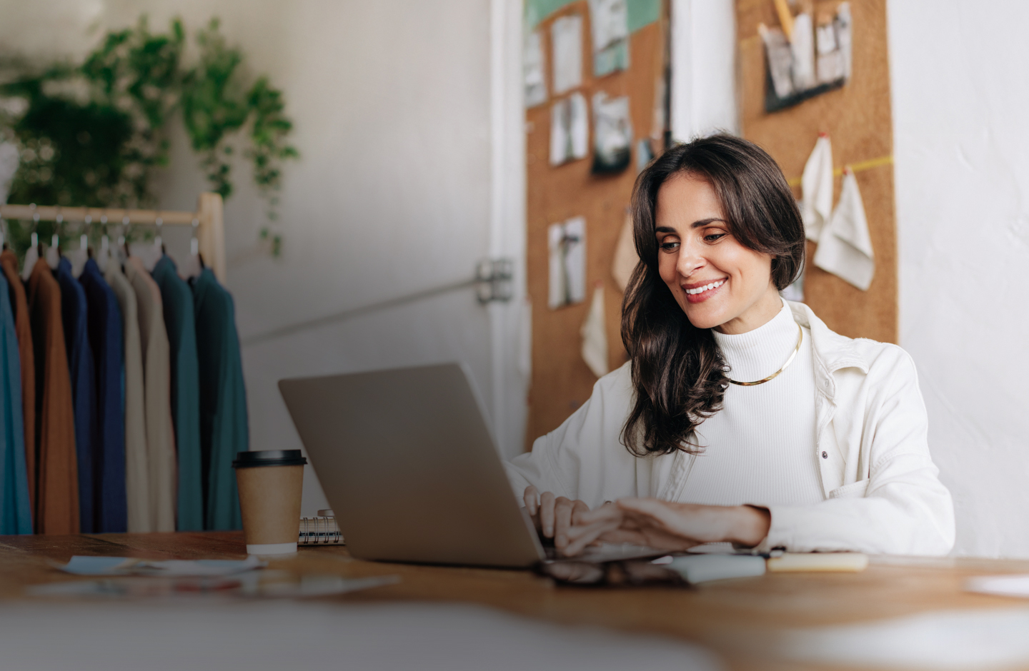 Eine Frau sitzt vor ihrem Laptop und lächelt während sie tippt.
